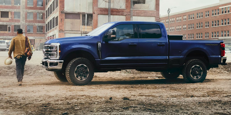 A blue Ford Tremor truck parked on a construction site with a person walking away