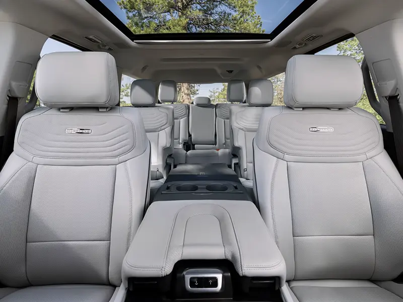 Interior view of full-size SUV with three rows of gray leather seats and panoramic sunroof