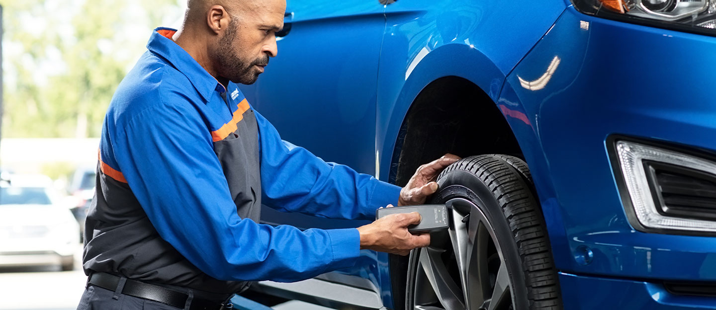 Technician inspecting car tire with device
